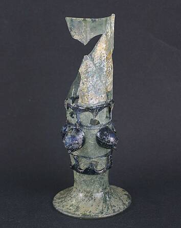 Fragment van een pijpglas dat is versierd met blauwe dierenkoppen uit de zestiende eeuw.