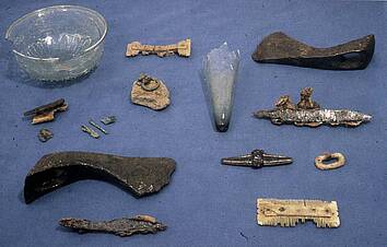 Diverse grafgiften, zoals bijlen, kammetjes en glazen voorwerpen, aangetroffen in twee vijfde-eeuwse kindergraven op het Pieterskerkhof. 