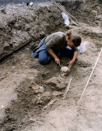 Bij een opgraving in 2000 worden tientallen graven gevonden op het Janskerkhof. Hier legt een archeoloog één van de graven met menselijke beenderen bloot.