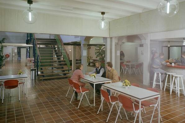 Oude foto uit de jaren 80 van een kantine met witte tafels en houten stoelen